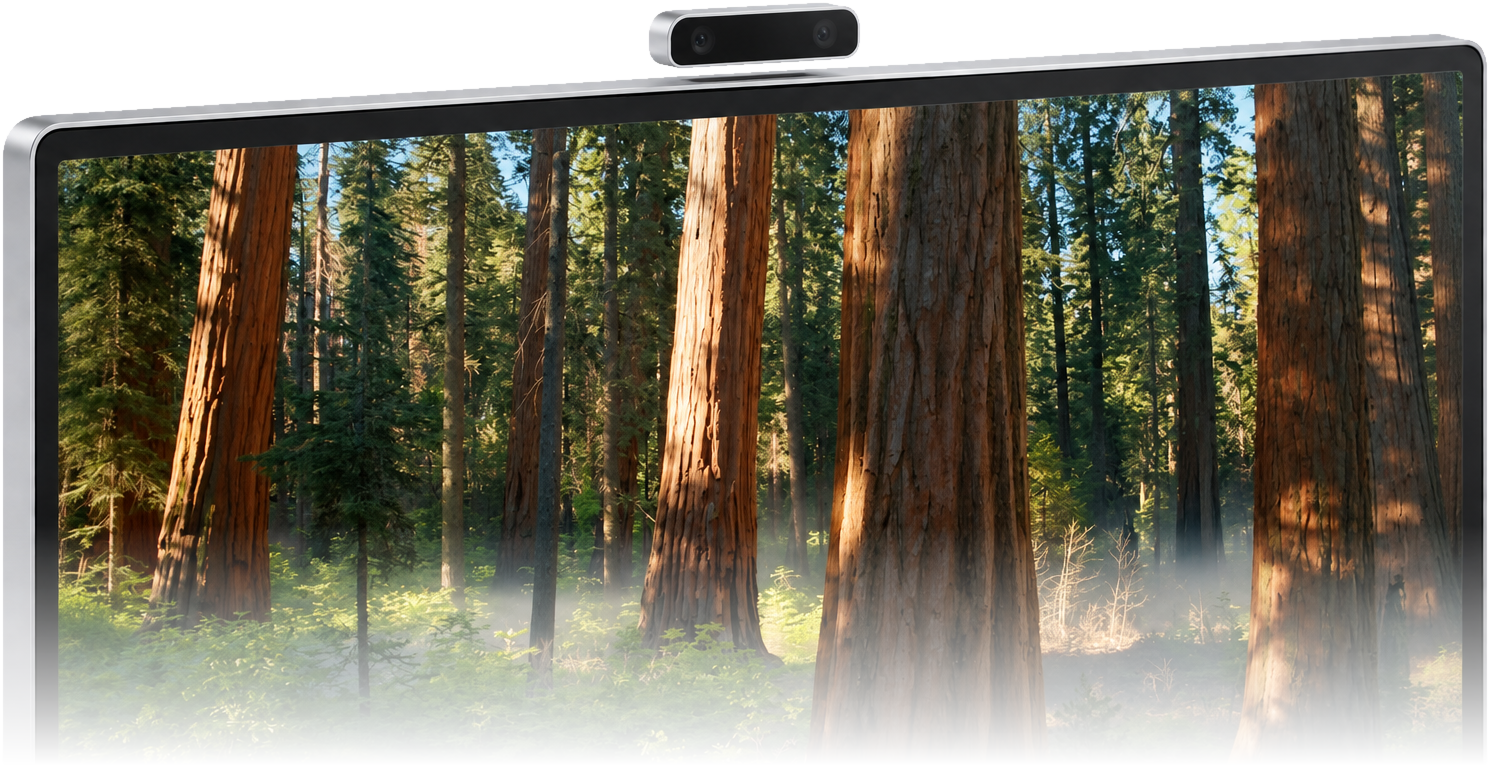 The Fovea Bar, a small camera bar with two lenses, resting on the top edge of a monitor.